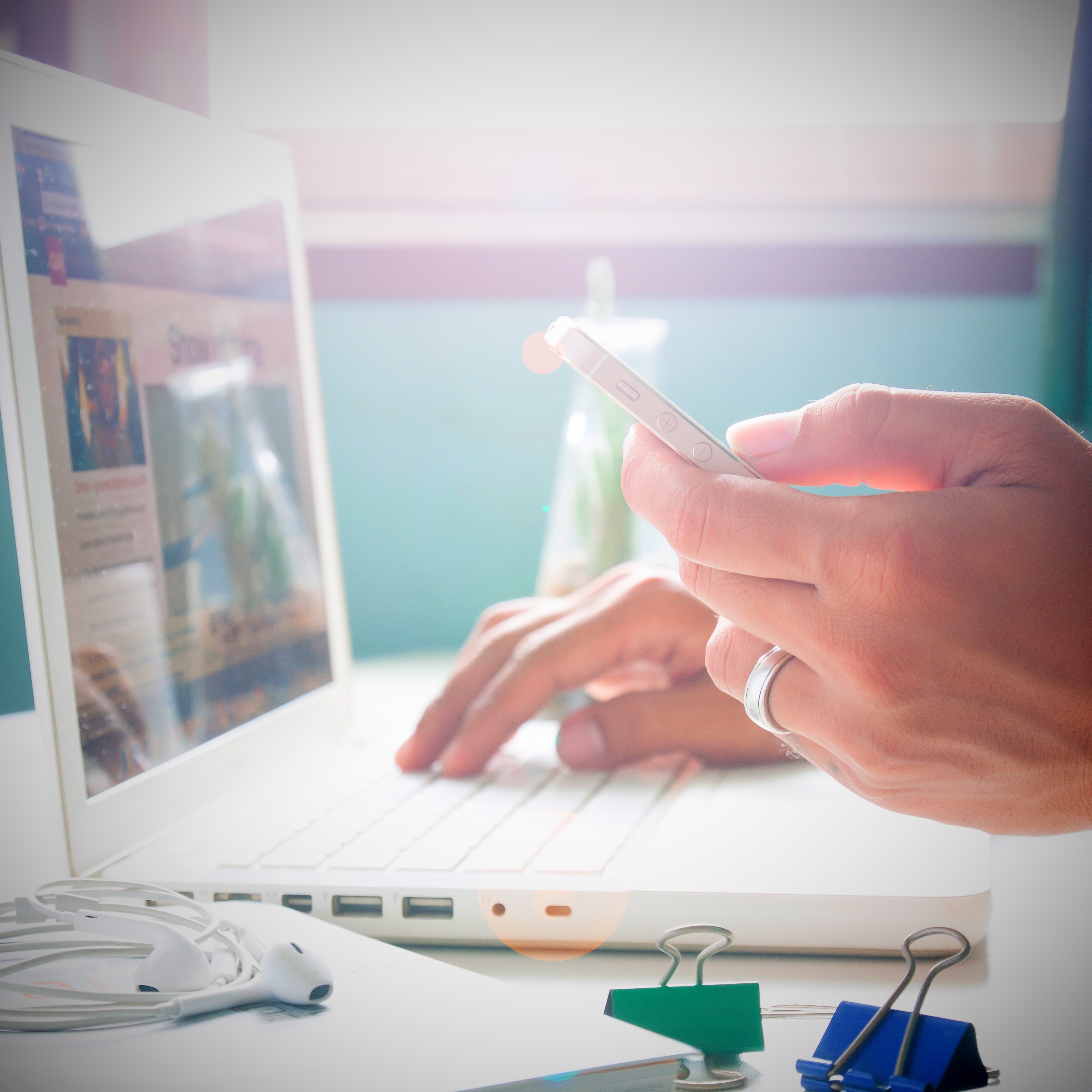 Man's hand holding smartphone and using laptop for online marketing Man's hand holding smartphone and using laptop for online marketing